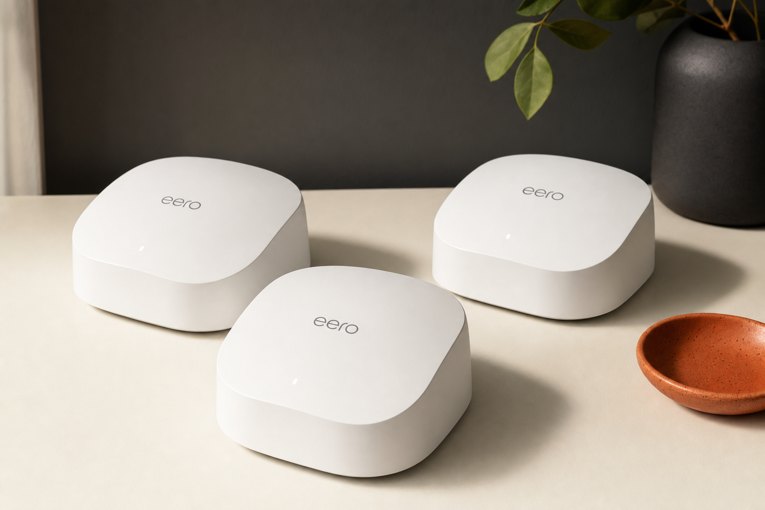 Three eero 6 mesh Wi-Fi units on a neutral surface from a three-quarter angle