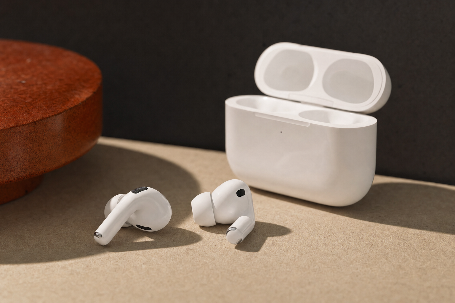 Apple AirPods Pro 3 earbuds and open charging case close-up on neutral surface